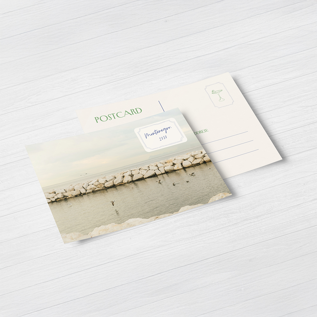 Postcard front and back on pale wood, front with stone breakwater and stamp-style label, back with POSTCARD heading, stamp box and address lines.