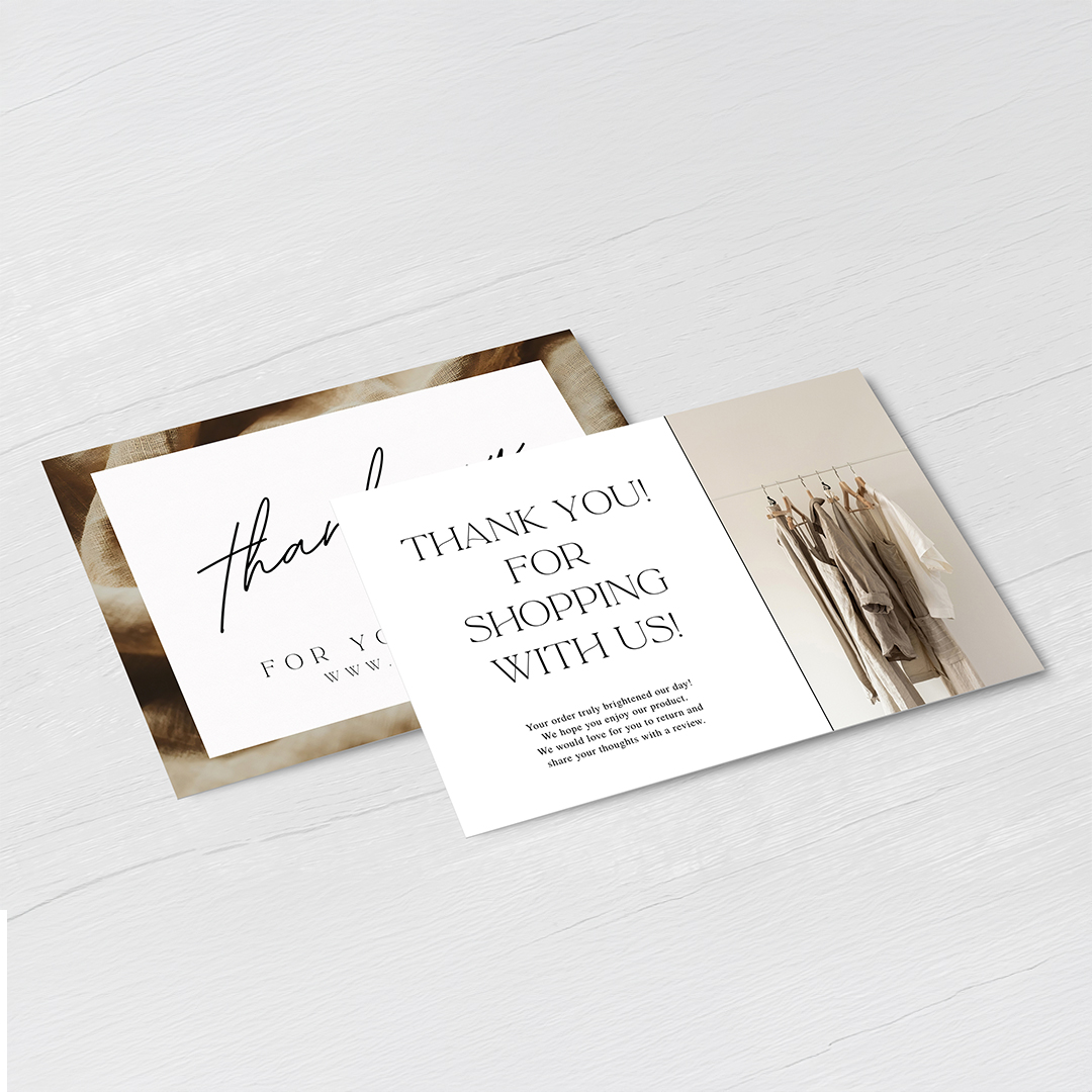 Two postcards on a pale gray wood surface, one with large script and one reading thank you for shopping with us beside a small clothes rail photo.
