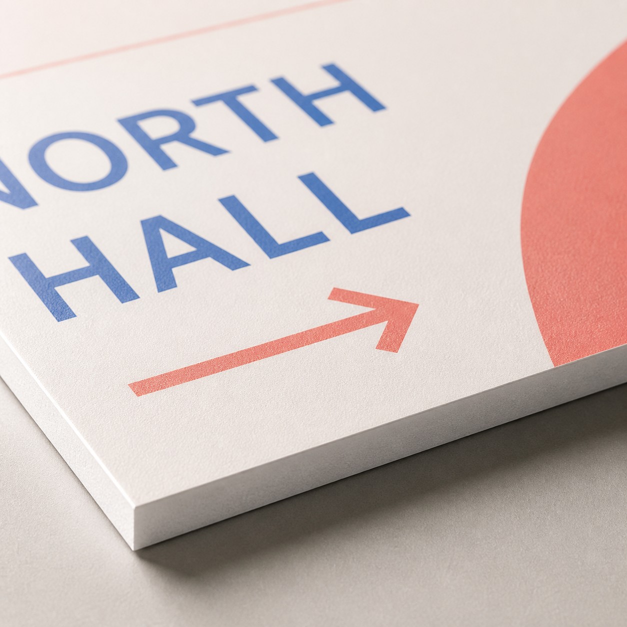 PVC sign panel edge close up with blue, coral red and cream print, thickness visible along cut edge, plain studio background