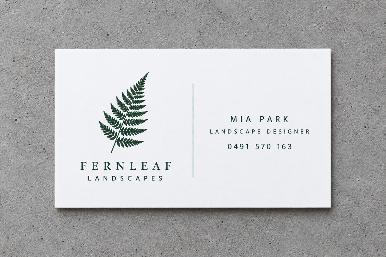 A bright white 100% recycled EcoStar business card printed with a green fern logo, lying on grey concrete