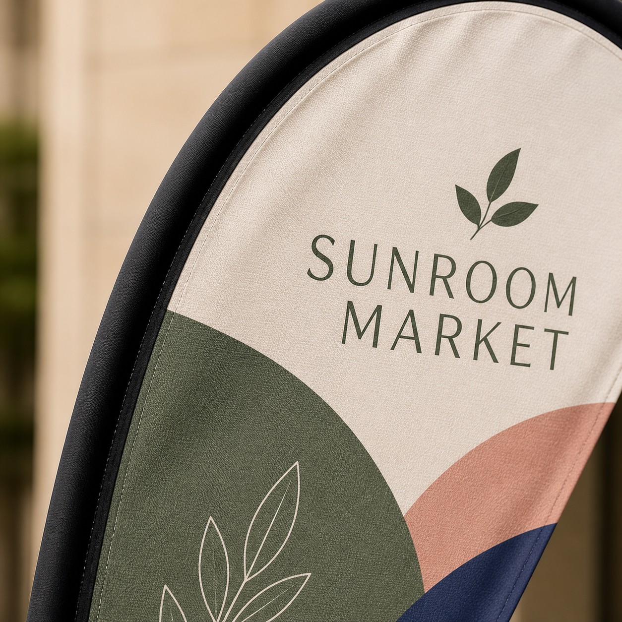 Teardrop banner close up with white teal orange and navy print, black binding along leading edge, visible fabric weave and foliage behind.