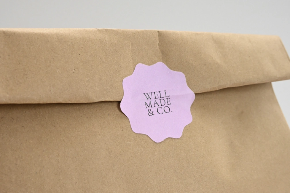Brown kraft bag sealed with a scalloped sticker · White Gloss or White Matte Sticker · No Laminate, Matte Laminate, or Gloss Laminate