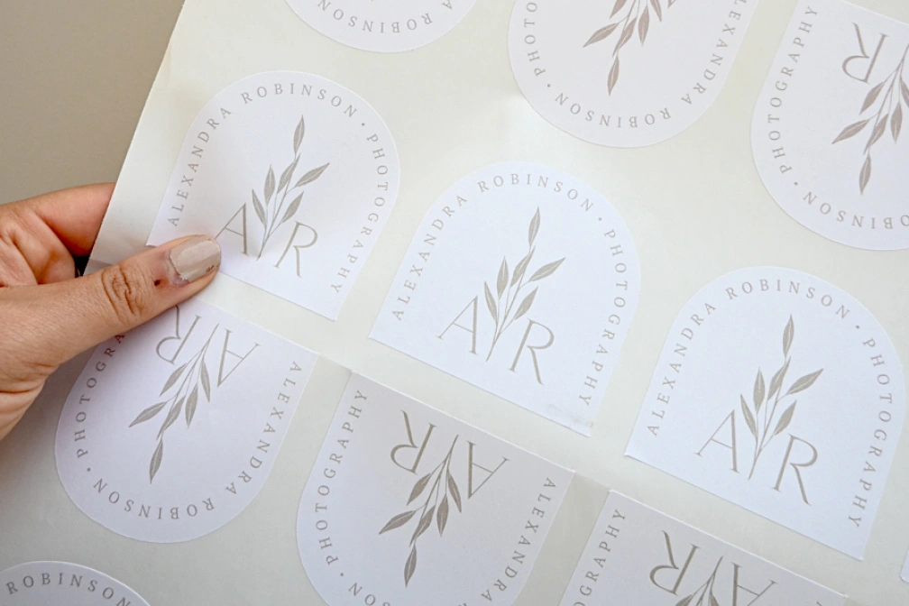 Hand holds a corner of a large kiss cut sticker sheet · White Gloss or White Matte Sticker · No Laminate, Matte Laminate, or Gloss Laminate