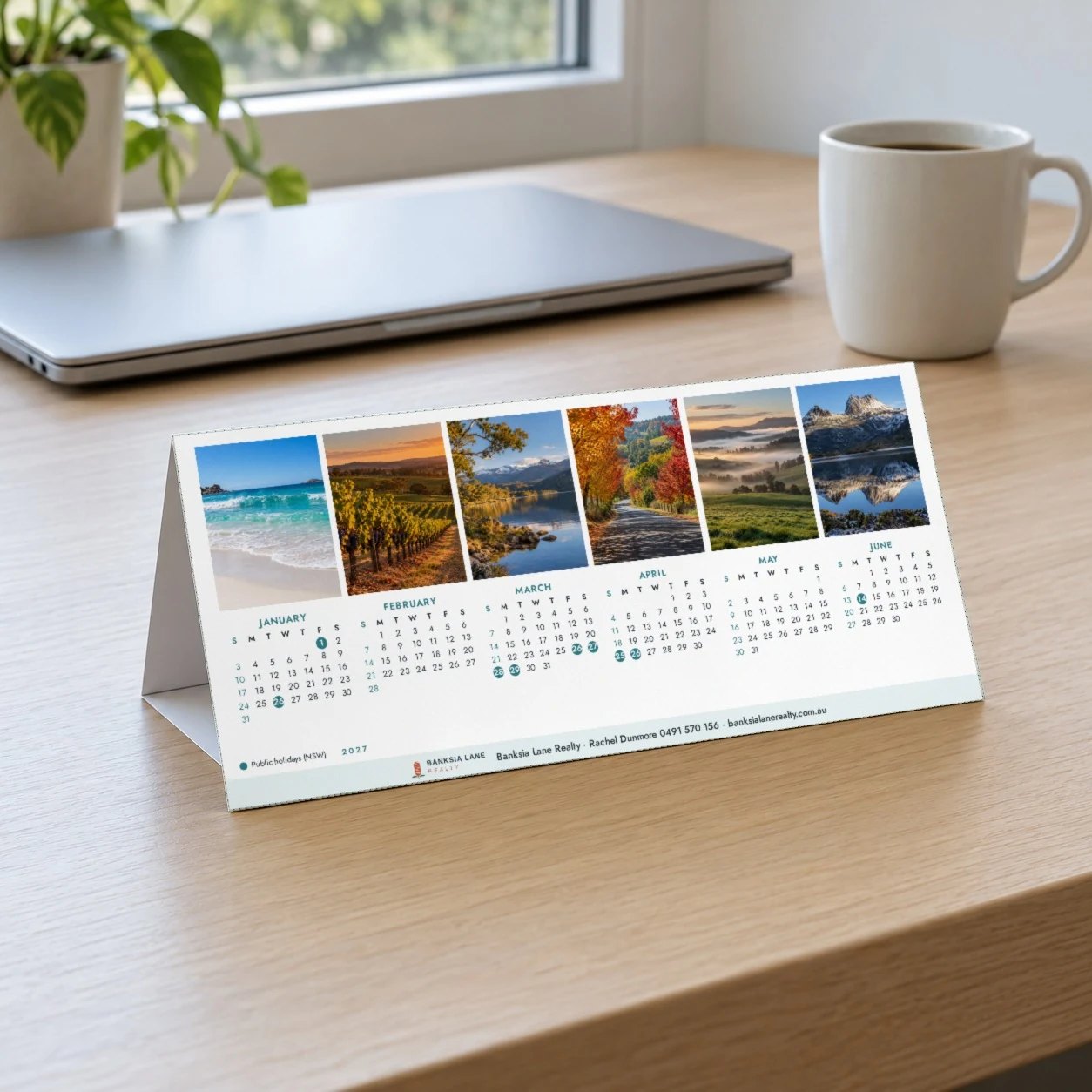 A4 tent desk calendar in Photo a month layout with six small landscape photos above six month grid on timber desk by window