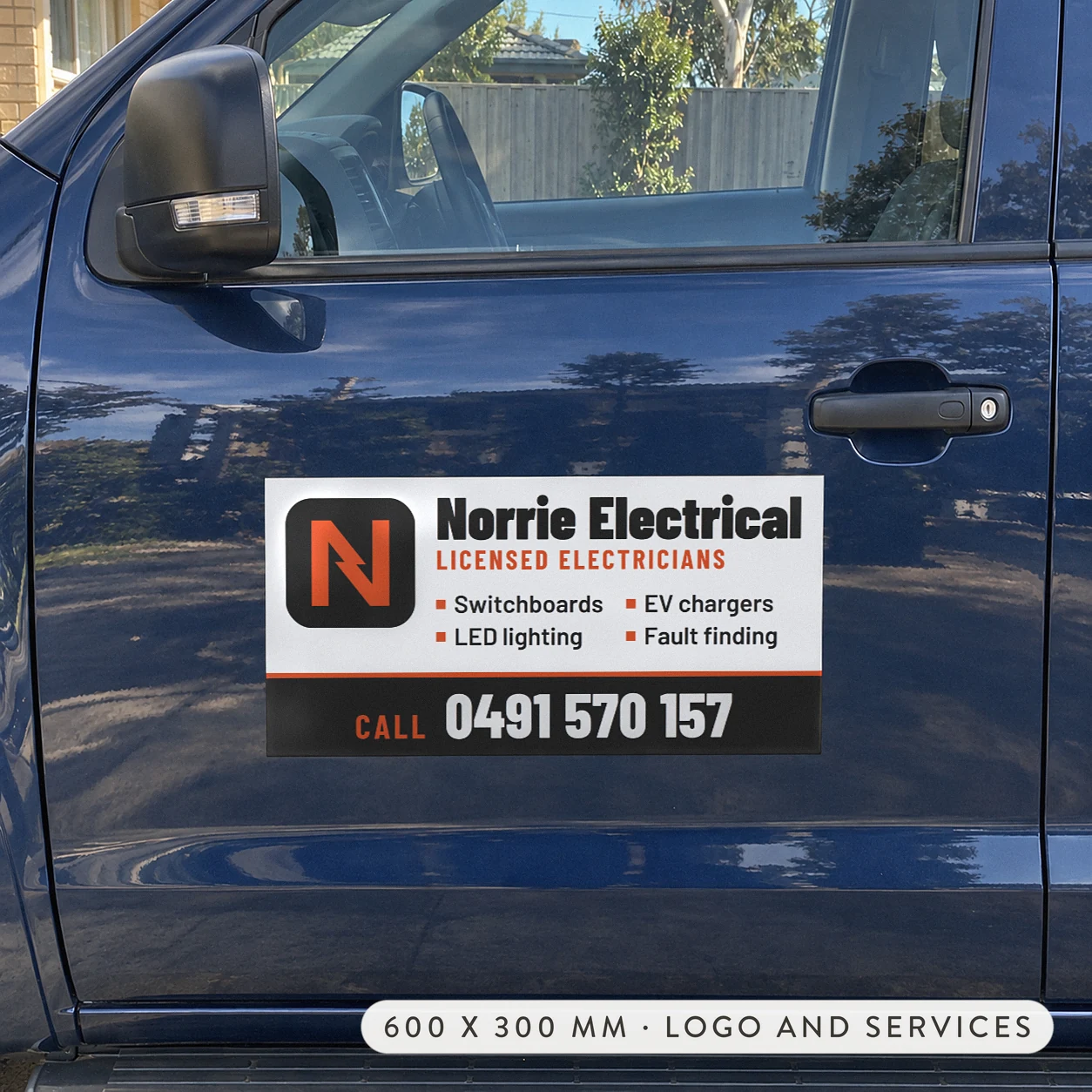 Magnetic car door sign on the front door of a dark navy ute, with an orange and black electrical logo and a band for a phone number.