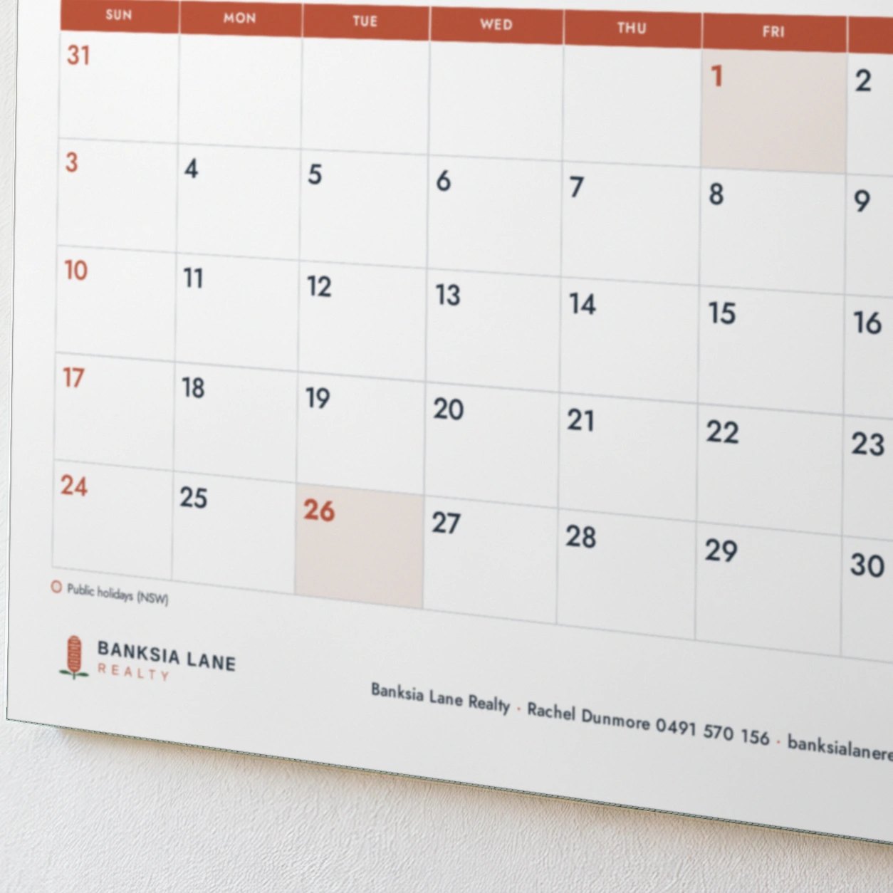 2027 wall calendar day grid under red day name row, two shaded public holiday boxes, footer with logo and one details line