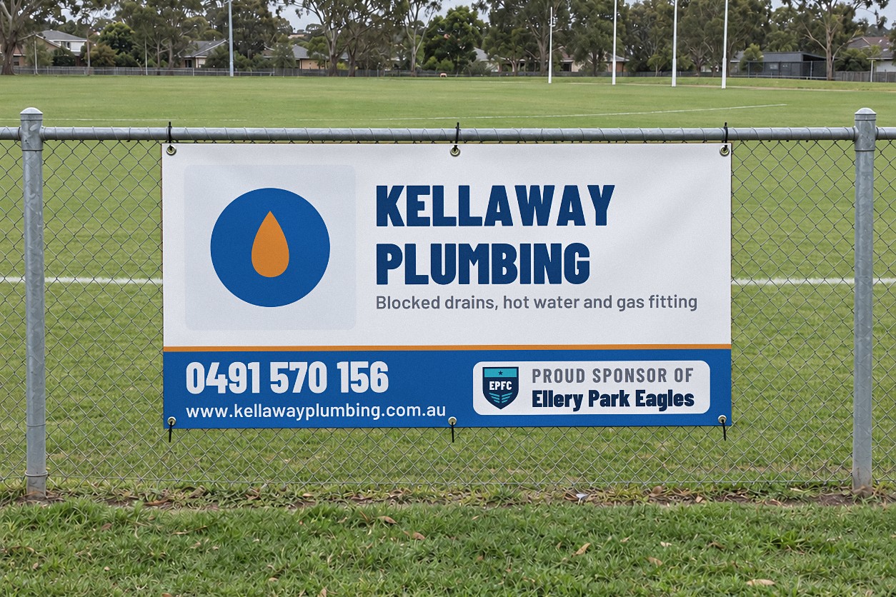 A white and blue vinyl sponsor banner cable tied through eyelets to a galvanised chain wire fence along a suburban oval