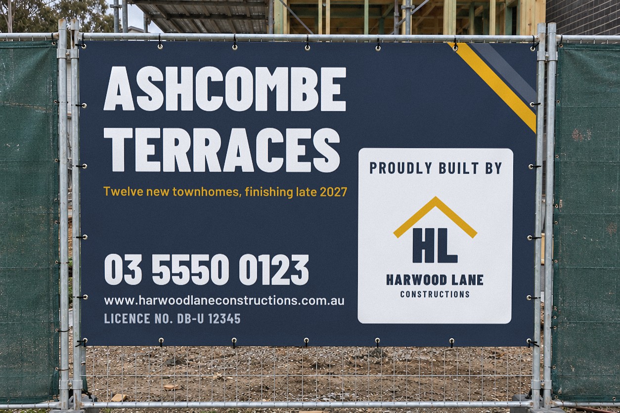 A navy mesh construction fence banner cable tied across a temporary fence panel in front of timber scaffolding