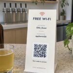 DL table talker on a terrazzo bar top, cream face reading FREE WI-FI, Wi-Fi QR code and printed network name and password