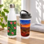 Custom water bottle with tropical leaves and pink hibiscus print beside white travel mug with outback sunset print